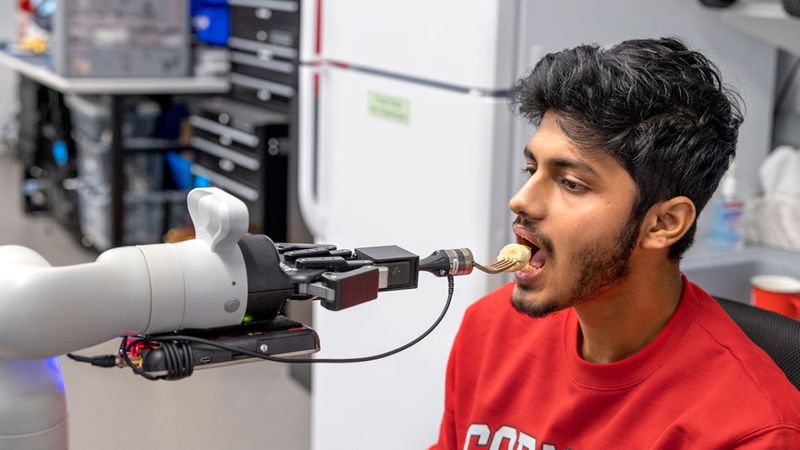 Doctoral student Rajat Kumar Jenamani, a member of Tapomayukh Bhattacharjee’s EmPRISE Lab, prepares to take a piece of a banana from an assistive robot prototype. Ryan Young/Cornell University