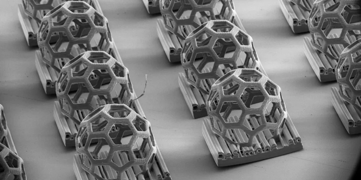 The 3D-printed DeSimone Lab logo, featuring a Buckyball geometry, demonstrates the r2rCLIP system’s ability to produce complex, non-moldable shapes with micron-scale features. | Image courtesy of DeSimone Research Group, SEM courtesy of Stanford Nano Shared Facilities