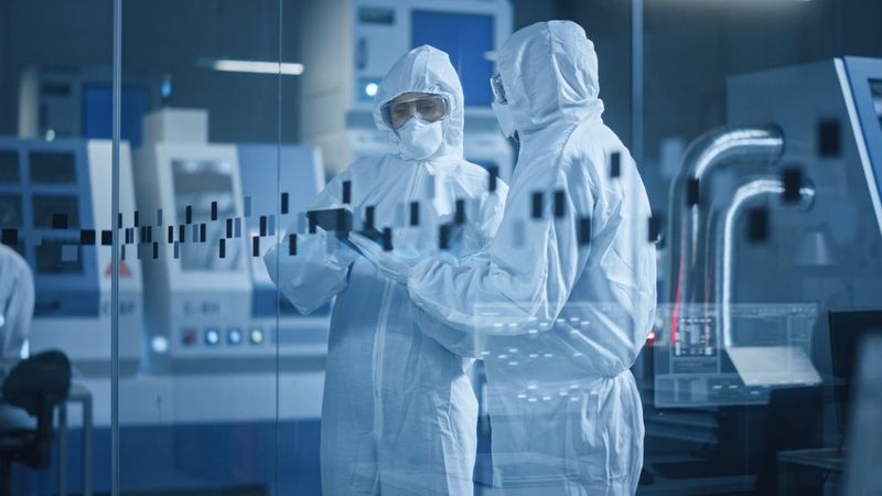 A view of a factory cleanroom featuring scientists wearing protective equipment