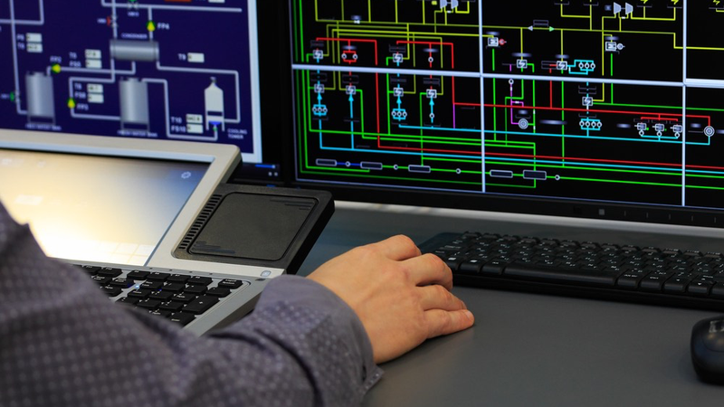 An engineer using SCADA to monitor and control industrial processes via PLC.