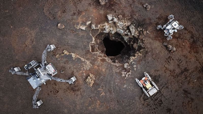 A drone's eye view of the DFKI rovers SherpaTT (left) and Coyote III (center) as well as LUVMI-X from Space Applications Services NV/SA (right) at the skylight