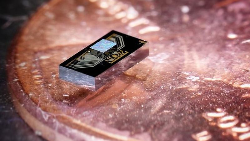 The chip sandwich: an electronics chip (the smaller chip on the top) integrated with a photonics chip, sitting atop a penny for scale. (Credit: Arian Hashemi Talkhooncheh)