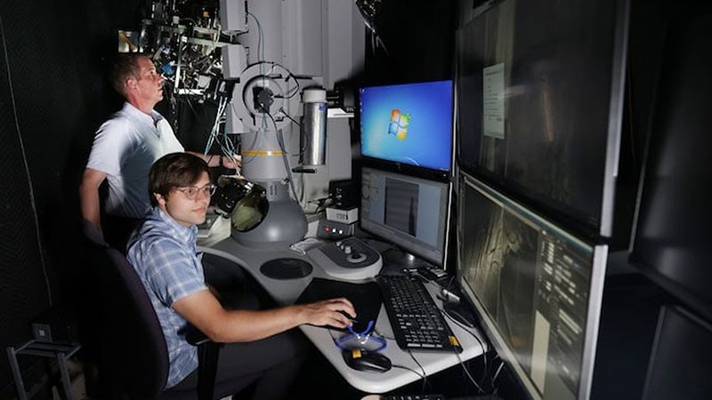Kevin Field, professor of nuclear engineering and radiological sciences, and Ethan Polselli, a doctoral student in the same department, work together in the Michigan Ion Beam Laboratory where the dual ion beam tests were conducted. Credit: Brenda Ahearn, Michigan Engineering.