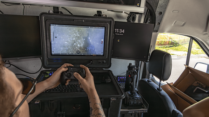 Operator using custom keyboard controls and laptop to pilot ROV remotely from control center.