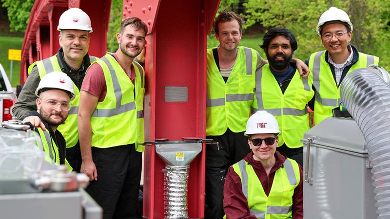 Members of the UMass Amherst and MIT research team pose next to the 3D-printed patch. Haden Quinlan (front, kneeling) of the Center for Advanced Production Technologies at MIT, is one of the researchers leading MIT’s efforts on the project. Photo: Alexia Cota/UMass Amherst