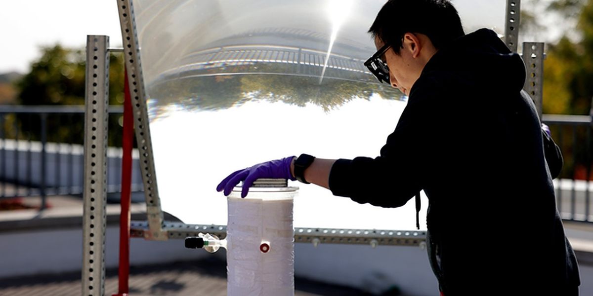 Peng Zhou uses a large lens to concentrate sunlight onto the water-splitting catalyst. Outdoors, the device was ten times more efficient than previous efforts at solar water splitting. Photo: Brenda Ahearn/Michigan Engineering, Communications and Marketing