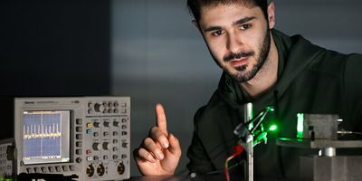 Researcher Riccardo Ollearo shows how the photodiode (right) picks up the signal from his finger, allowing him to see how fast his heart is beating on the screen (left). (Photo: Bart van Overbeeke)