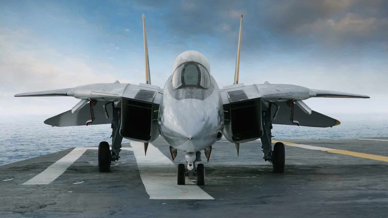 An F/A-18 Super Hornet fighter jet sits onboard an aircraft carrier deck sailing the ocean.