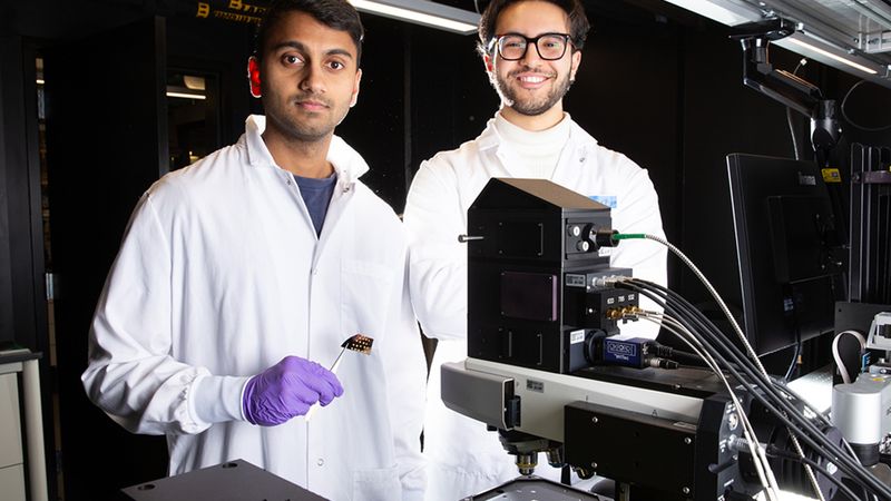 MIT MechE Postdoctoral Associate Aditya Garg (left) and MechE Doctoral student Seleem Badawy stand behind the Raman microscope used to evaluate the Plasmosniff chip. Photo: Tony Pulsone