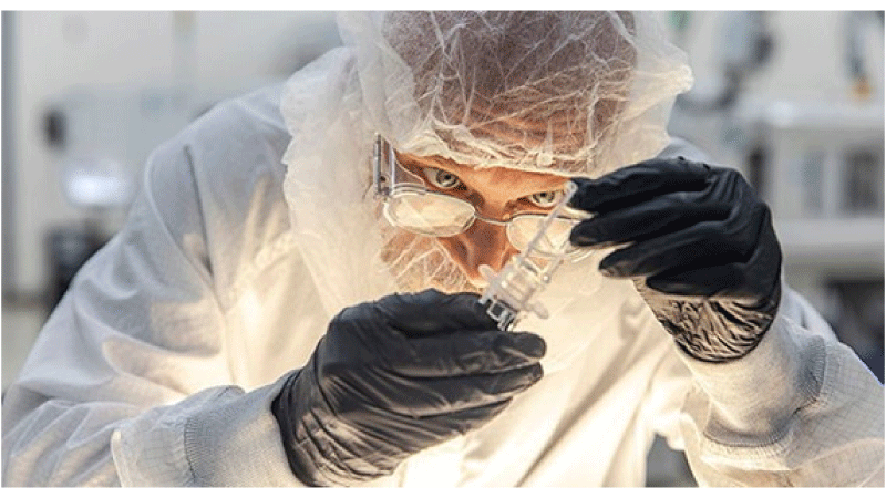 A quality technician examines a plastic part in a clean room during the medical moulding process to ensure precision and repeatability.