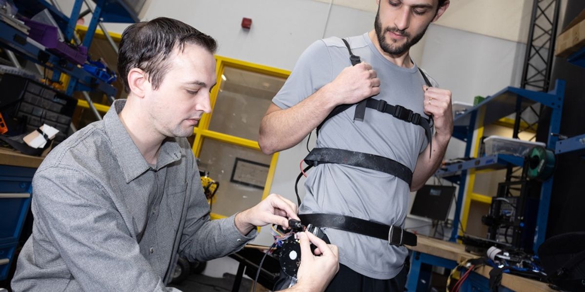 Researcher Aaron Young makes adjustments to an experimental exoskeleton worn by then-Ph.D. student Dean Molinaro. The team used the exoskeleton to develop a unified control framework for robotic assistance devices that would allow users to put on an "exo" and go — no extensive training, tuning, or calibration required. (Photo: Candler Hobbs)