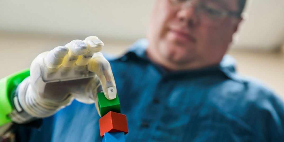 Joe Hamilton, a participant in the University of Michigan RPNI study, naturally uses his mind to control a DEKA prosthetic hand to pick up a small block. Photo: Evan Dougherty/University of Michigan Engineering