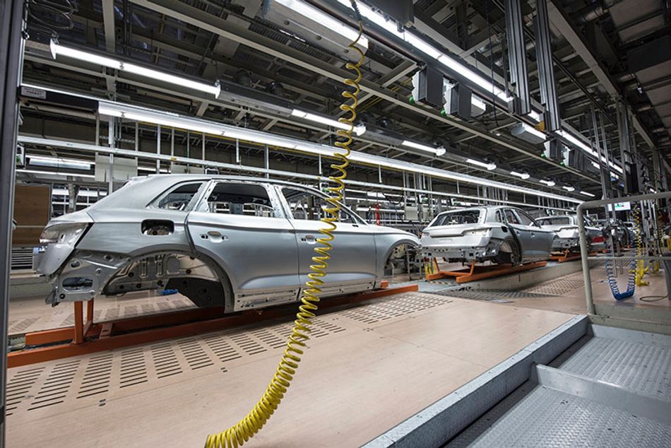 Unpainted cars are suspended in a manufacturing row.