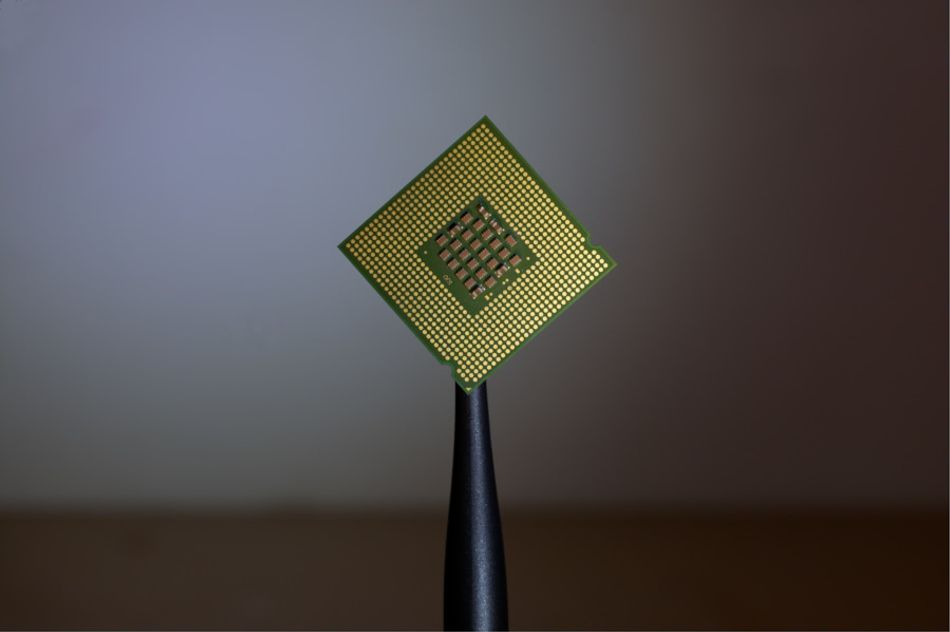 A photograph of a computer processor, pin-side to camera, held in a stand so as to show as a diamond shape.