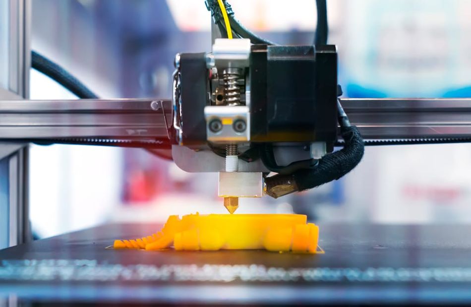 3D printer hotend extruding yellow filament.