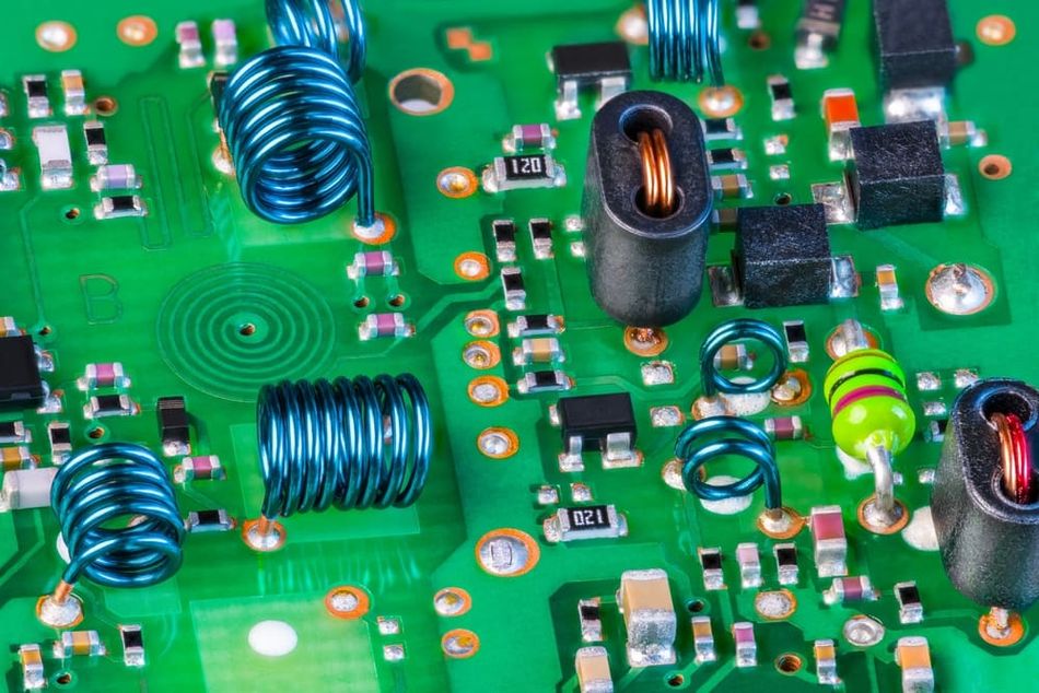 Green printed circuit board (PCB) with electronic components for radio-frequency (RF) signal reception.  The PCB contains planar spiral coils, air-core inductors, and surface-mount components.