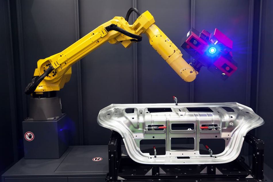 A yellow robot arm with built in 3D scanner during an automated scanning.
