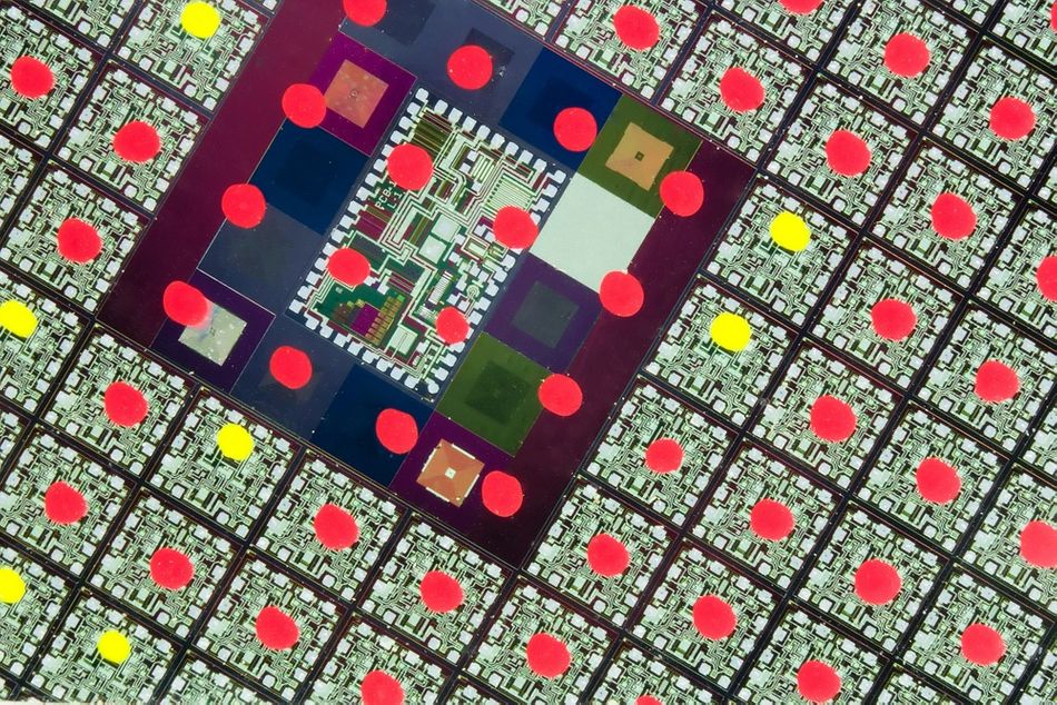 Extremely close-up of a large-scale integrated circuit wafer with quality control marks clearly visible on the surface.