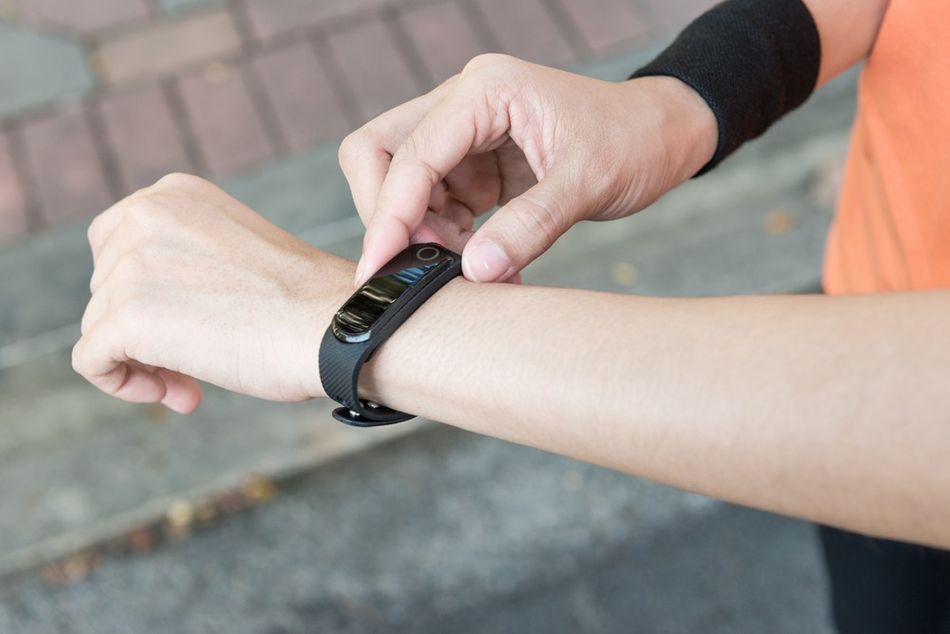 A runner putting on heart rate monitor wrist watch