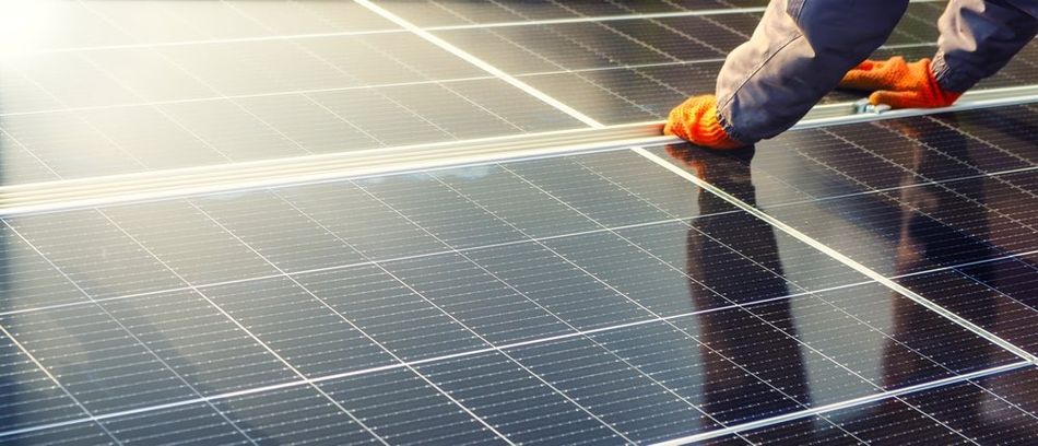 Close-up view of a solar cell being installed in a solar farm power plant, showcasing eco-friendly technology. The image features solar cell panels arranged in a photovoltaic power plant, emphasizing the concept of sustainable resources. A pair of hands belonging to a worker are visible, actively involved in the installation process.