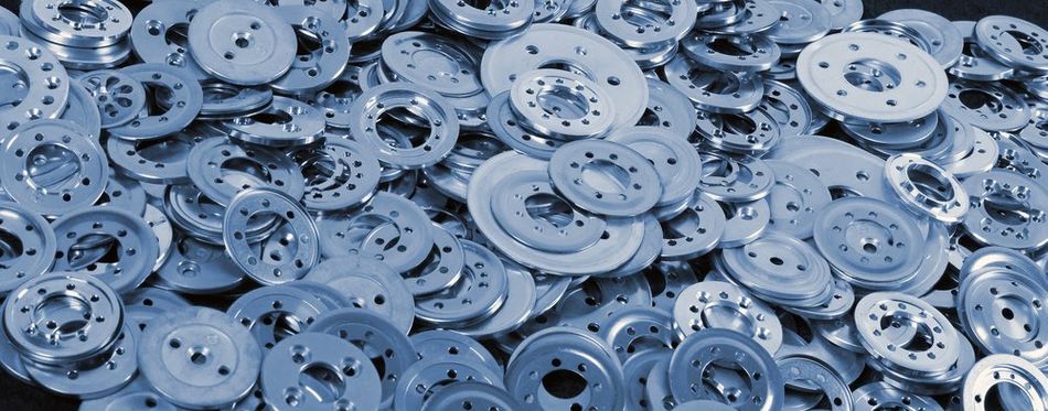 Image depicting an assortment of blue aluminum spacers and washers (aluminium shims) arranged in a stack against an industrial backdrop.