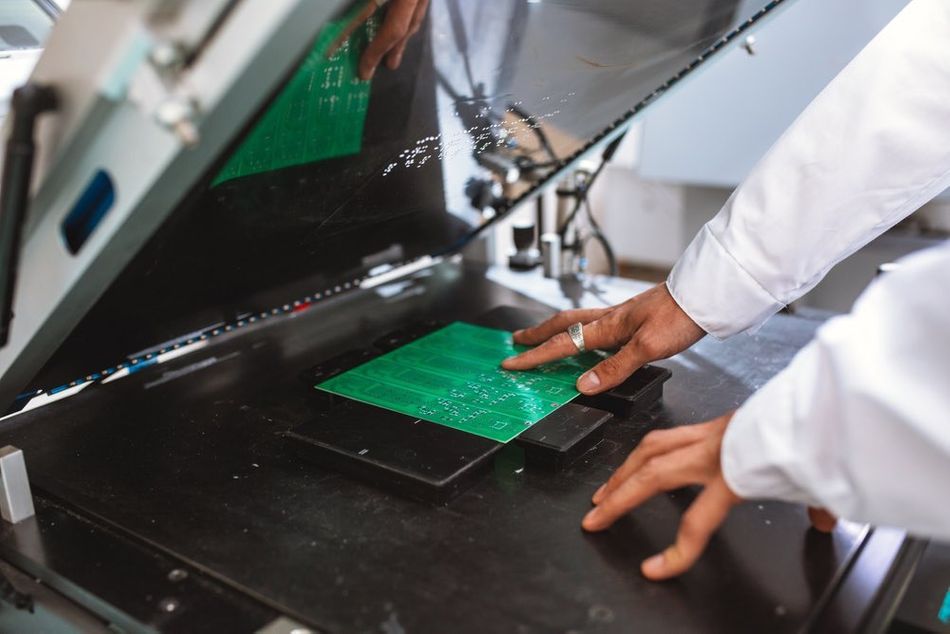 A designer loading a PCB into a screen printing machine for silkscreen application 