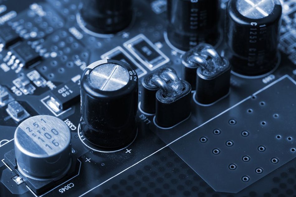 A close-up view of a Printed Wiring Board (PWB) populated with various electronic components, including an Application Specific Integrated Circuit (ASIC), inductors, chip capacitors, electrolytic capacitors, and chip resistors