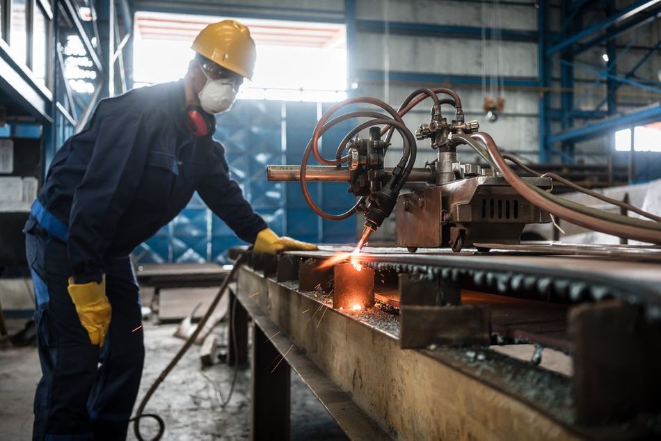 A worker wearing the essential PPEs while working with a plasma cutter