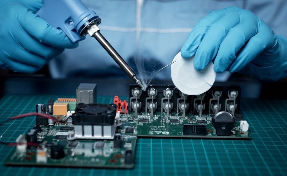 A technician wears rubber gloves to ensure soldering safety