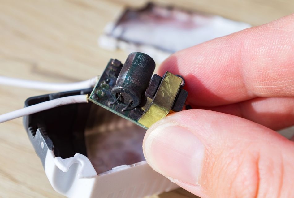 Burnt and soot-charred capacitor on PCB, possibly due to fire, or short circuit