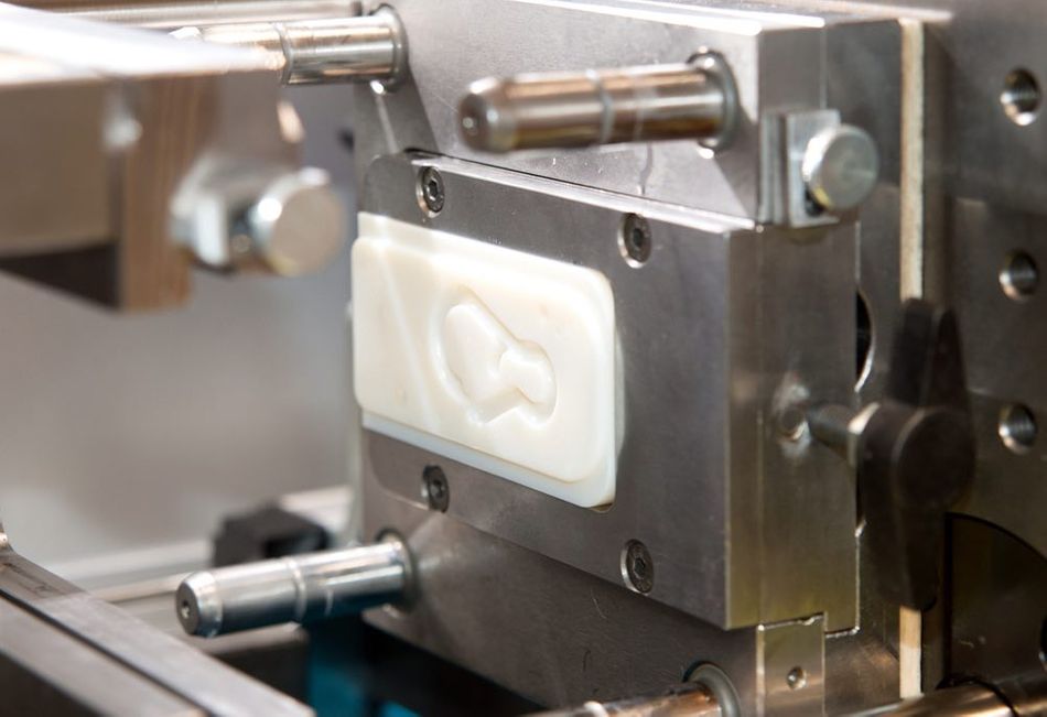 A close-up of a machine containing a white-colored 3D-printed mold.