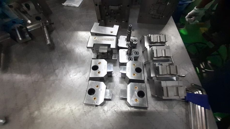 A group of metal mold and insert parts on a metal surface.