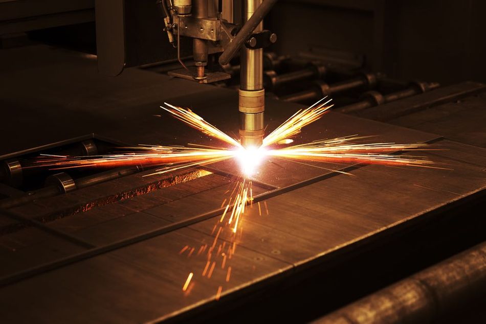 Industrial CNC plasma cutting of a metal plate, with a plasma arc resembling a bright, intense light at the point where the tool interacts with the plate.