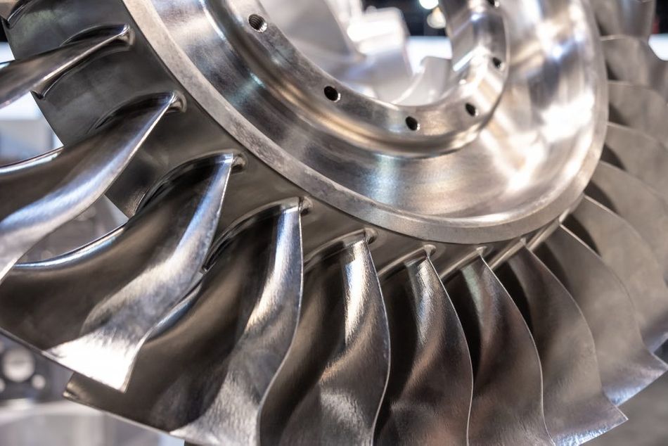 A close-up view of a turbine disk with blades crafted from polished metal, exhibiting a shiny surface.