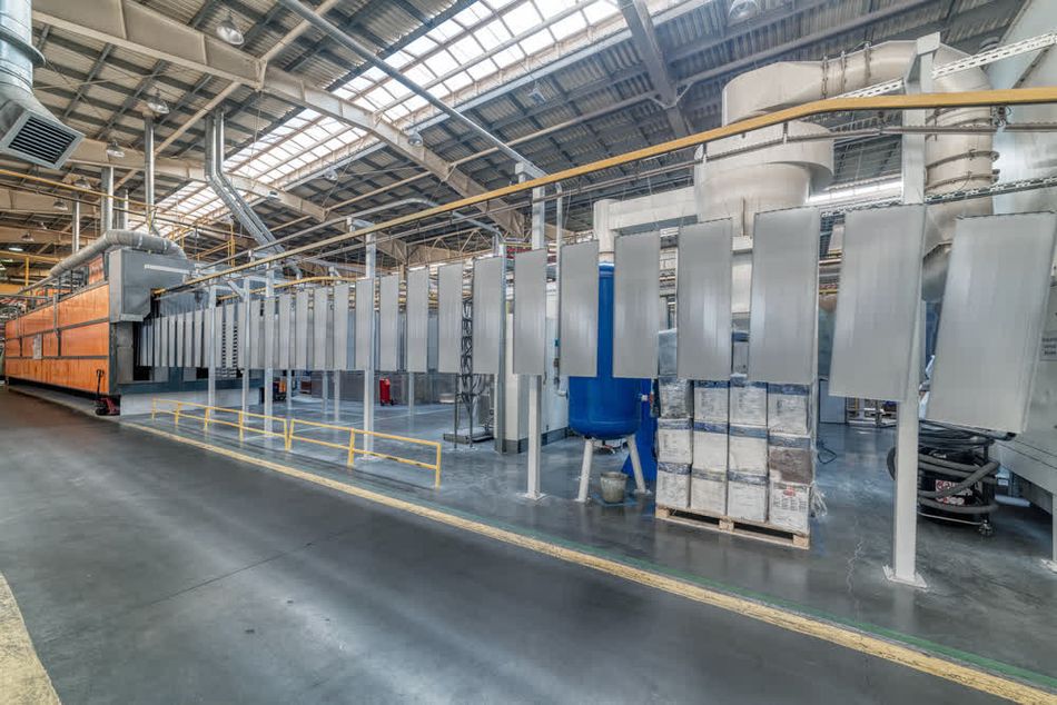 Metal panels suspended on an overhead conveyor line in an industrial setting for electrostatic powder coating.