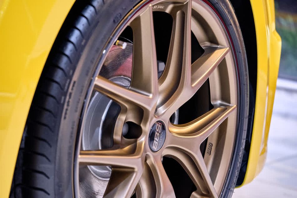 Detailed view of a yellow car wheel, highlighting the bronze-colored, powder-coated aluminum alloy rim.