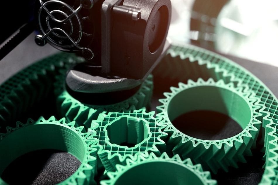 Machine gears in close-up, showcasing an intricate assembly of interlocking green gears with a mechanical component in the foreground.
