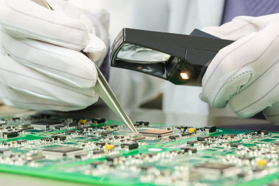 A tester visually inspecting a PCB for solder and connection quality