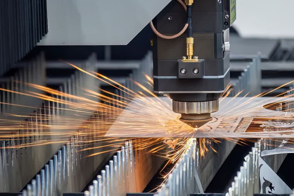 A fiber laser cutting machine in action, slicing through a metal plate with bright sparks flying. The image illustrates the high-speed and precision capabilities of laser technology in modern sheet metal manufacturing.