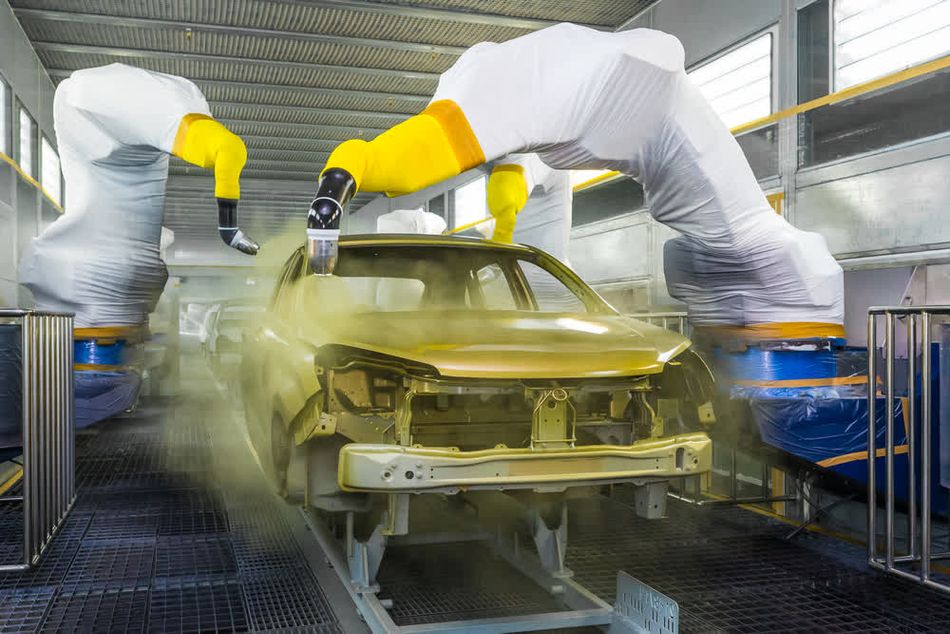 A set of robotic arms painting the body of a car