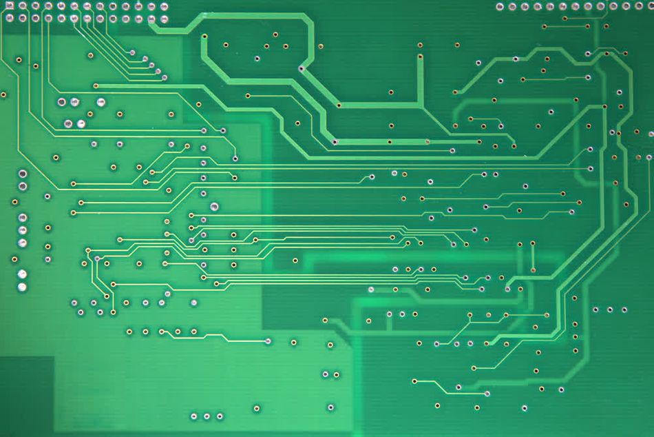 Close-up inspection of a bare PCB with a green photoresist coating. This crucial step verifies the circuit design accuracy before etching and transforming it into a fully functional electronic board.