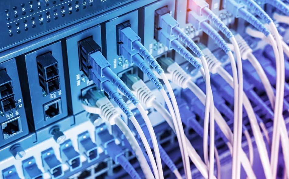 Close-up view of fiber optic cables plugged into optical ports alongside network cables connected to Ethernet ports.