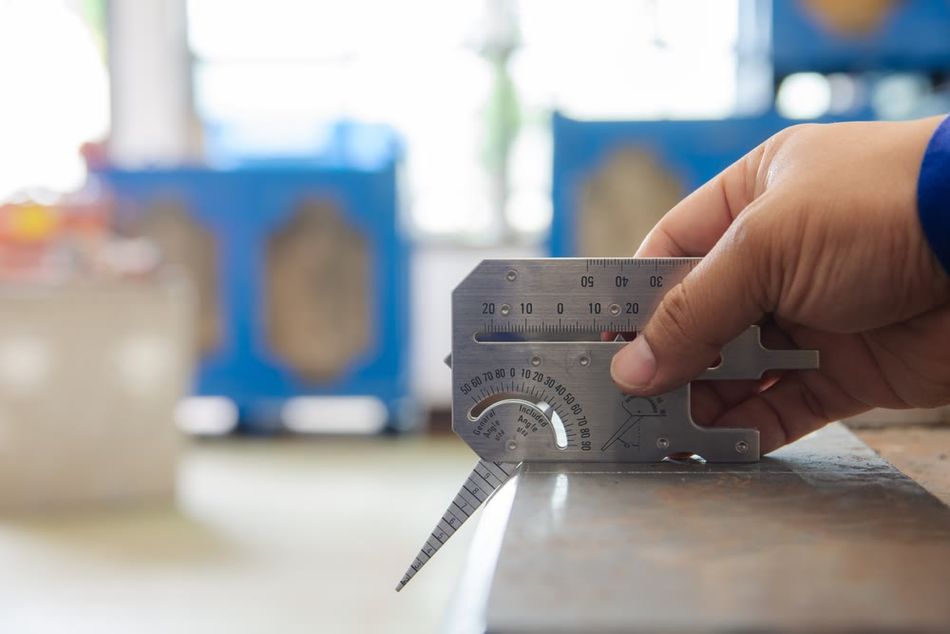 A quality inspector measuring the chamfer angle on an external edge