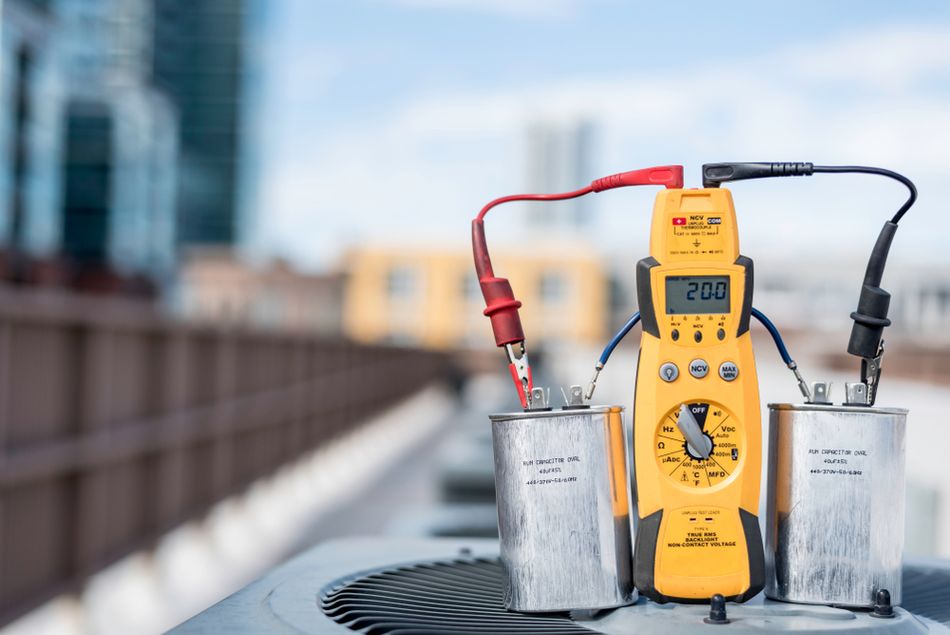 Multimeter Testing Two Run Capacitors Wired in Series