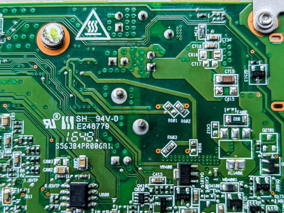 Close-up image of a green printed circuit board (PCB) showing densely packed electronic components, intricate copper traces, and solder points. The precision of the etched copper pathways highlights the importance of accurate etch rates, undercut control, and yield optimization in PCB manufacturing.