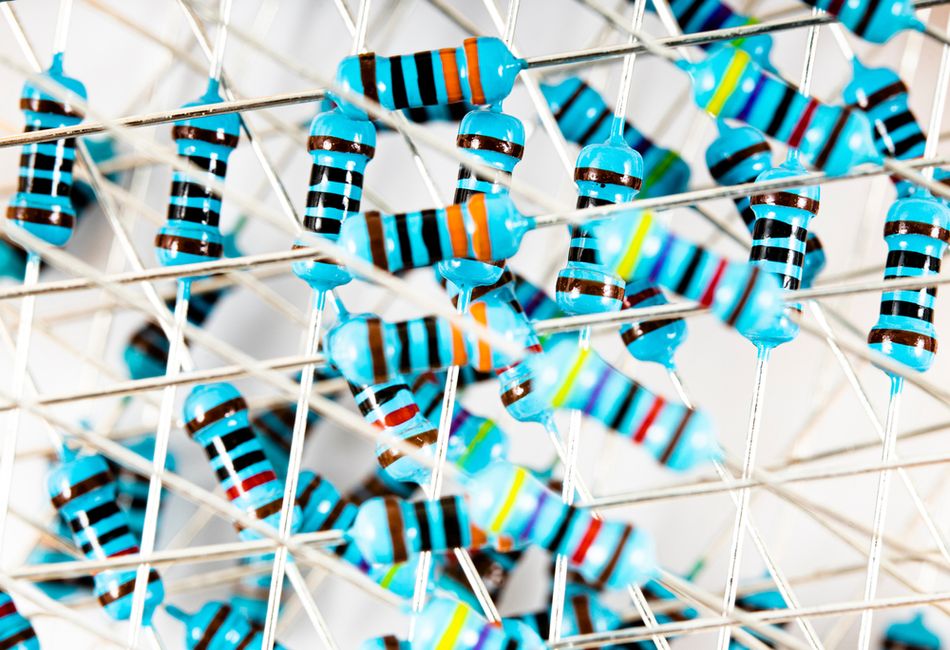 Close-up view of multiple blue, color-banded through-hole resistors arranged in a grid, showing their leads and painted bands used to indicate resistance values in electronic circuits.