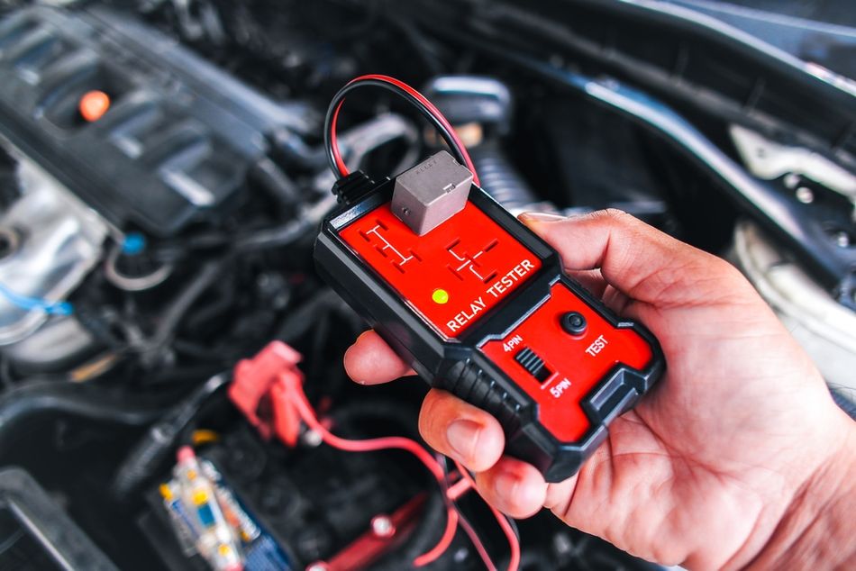 A technician testing a car relay with special testing equipment