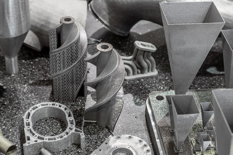 Various additively manufactured metal parts surrounded by metal powder.