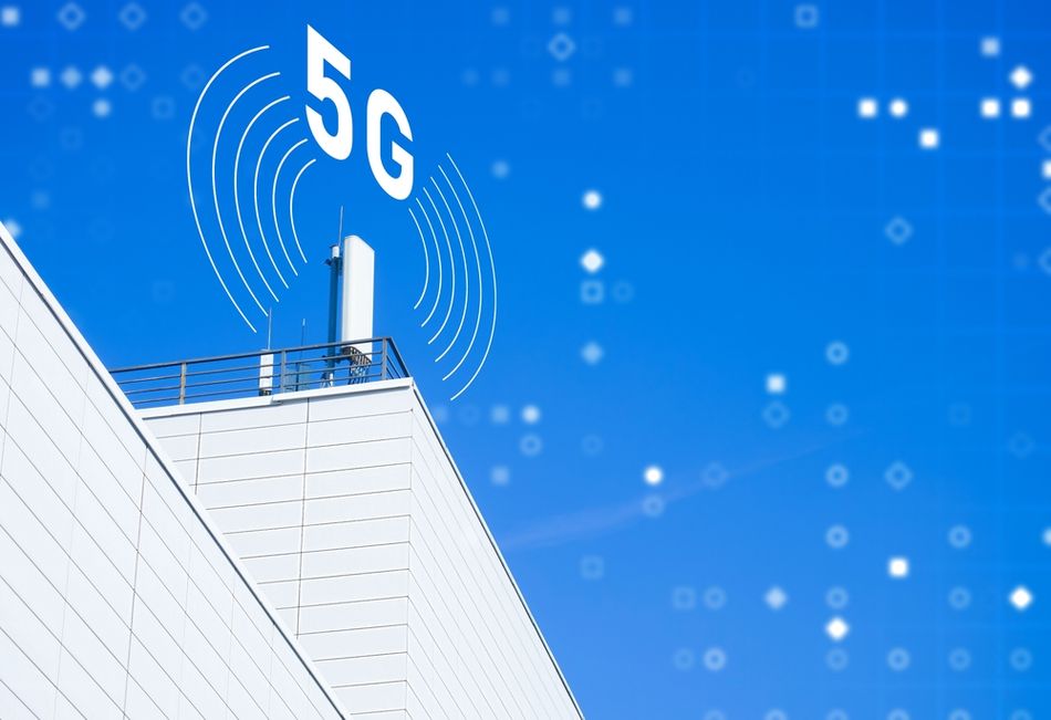 A rooftop 5G antenna against a blue sky with a large 5G symbol and wireless signal graphics, representing high-speed wireless communication and telecommunications network connectivity.