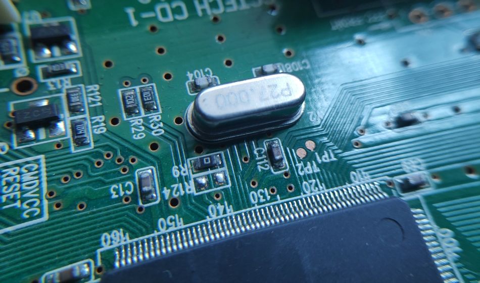 Crystal oscillator mounted among electronic components on a printed circuit board.